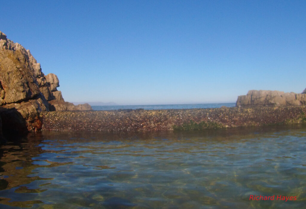 A view of the water and the low wall separating the sea from the tidal pool
