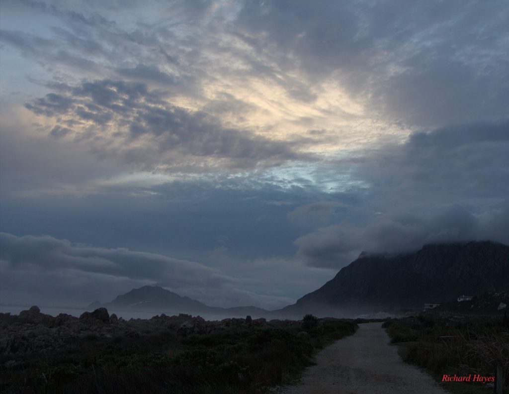 Sunset clouds over a mountain with mist banks lower down.