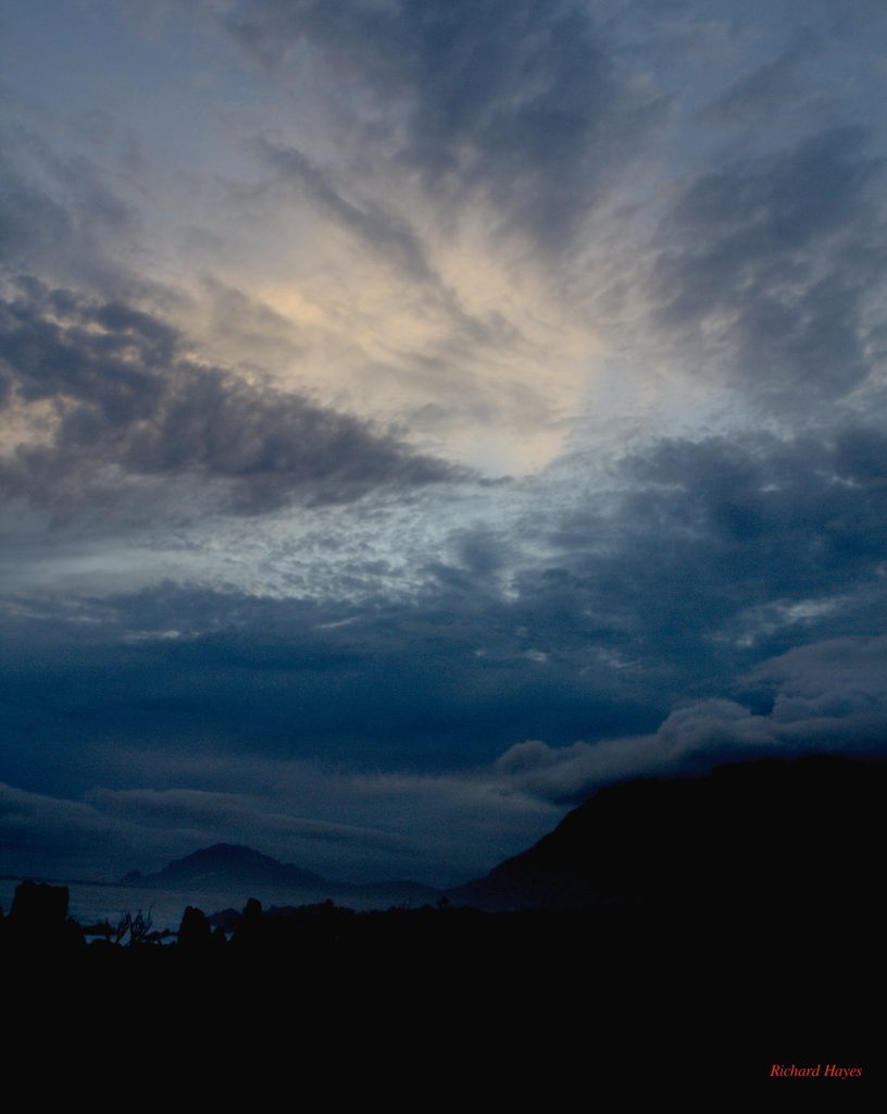 Sunset clouds over a mountain with mist banks lower down.